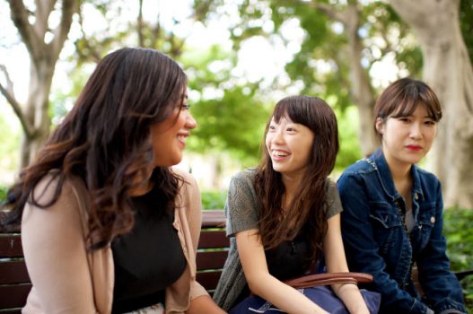 Three women laughing on a park bench