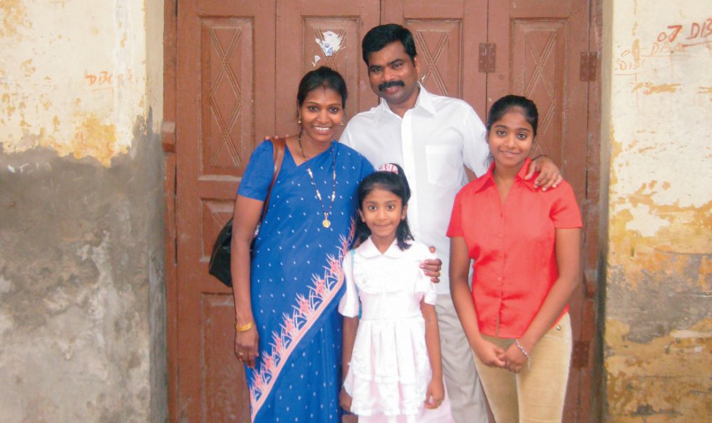 Family of four standing in front of door in New Delhi.