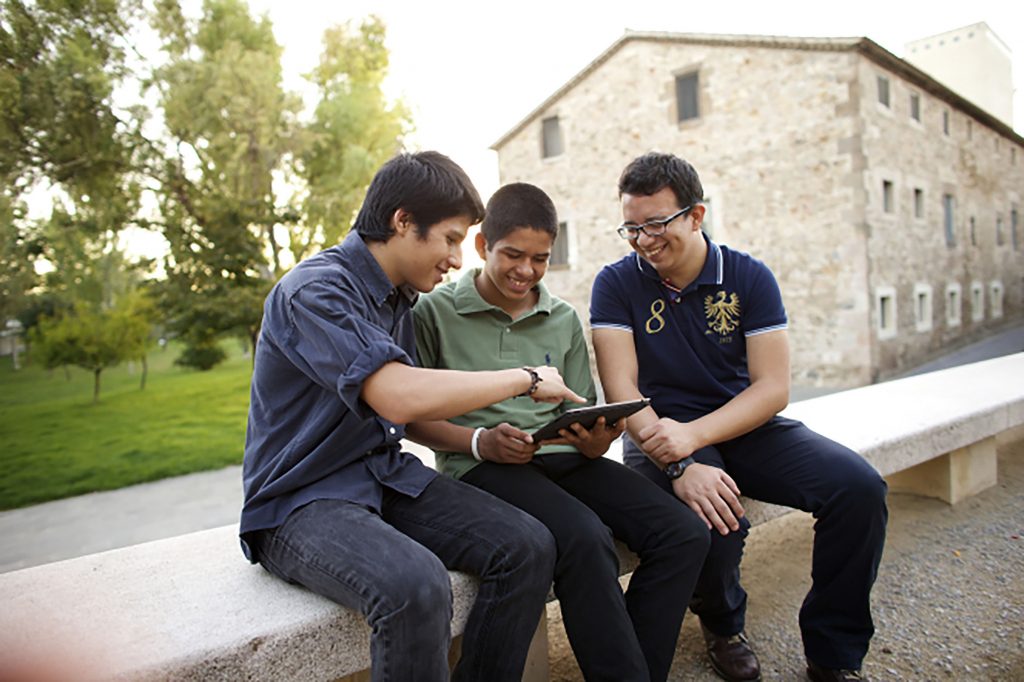 three young men on a tablet, smiling and looking at things
