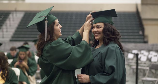 two girls at graduation in green gowns