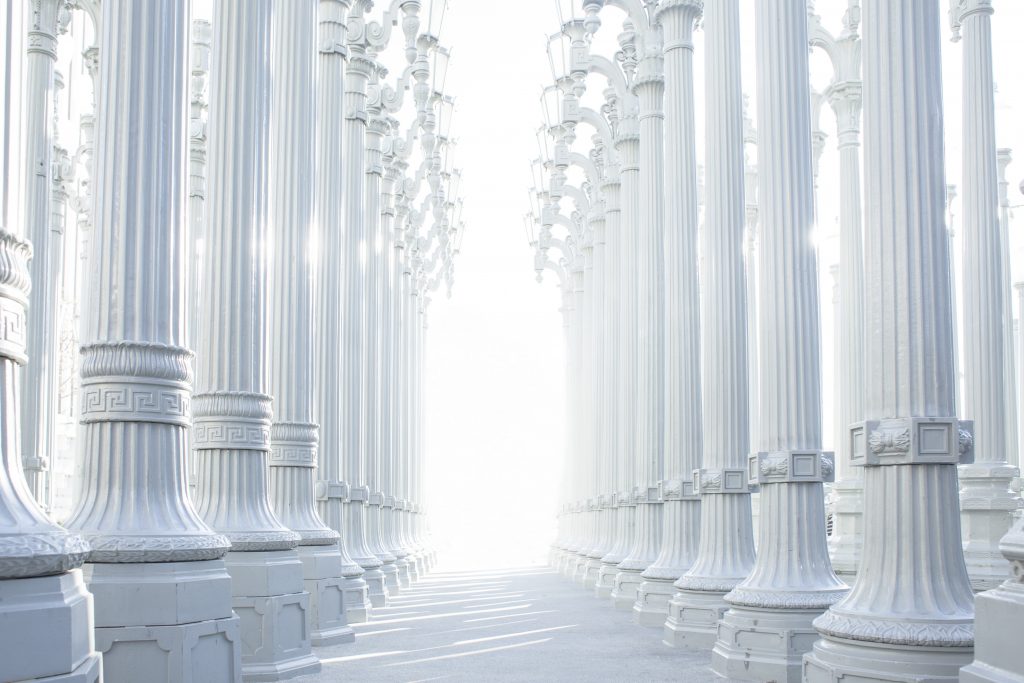 brilliant light shines at the end of a row of white columns
