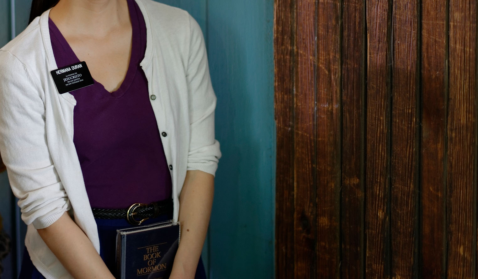 a sister missionary seen from the neck down holds a Book of Mormon