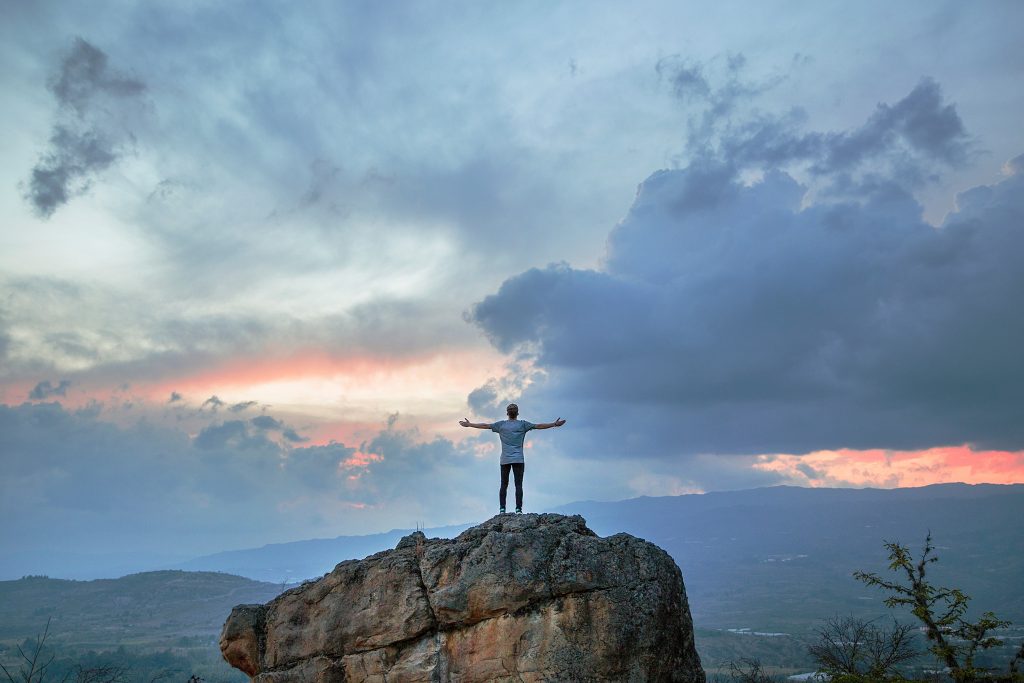 man atop a mountain with sky