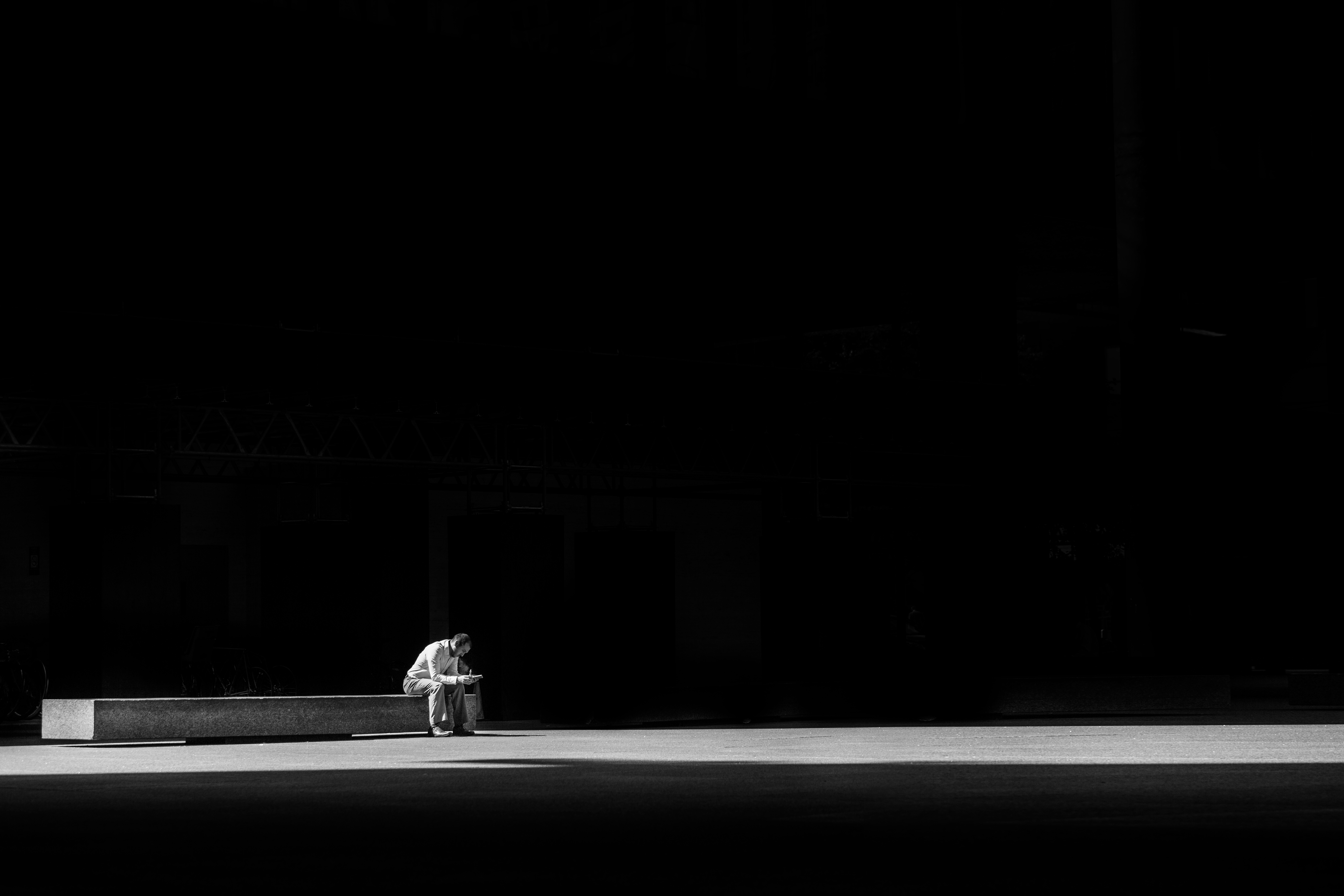 Man sitting alone on bench in darkness