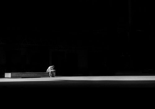Man sitting alone on bench in darkness