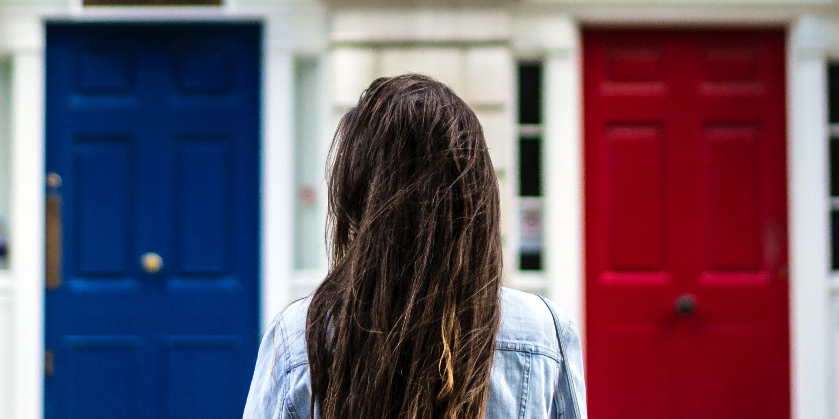 Girl standing in front of three doors (blue, white, and red)