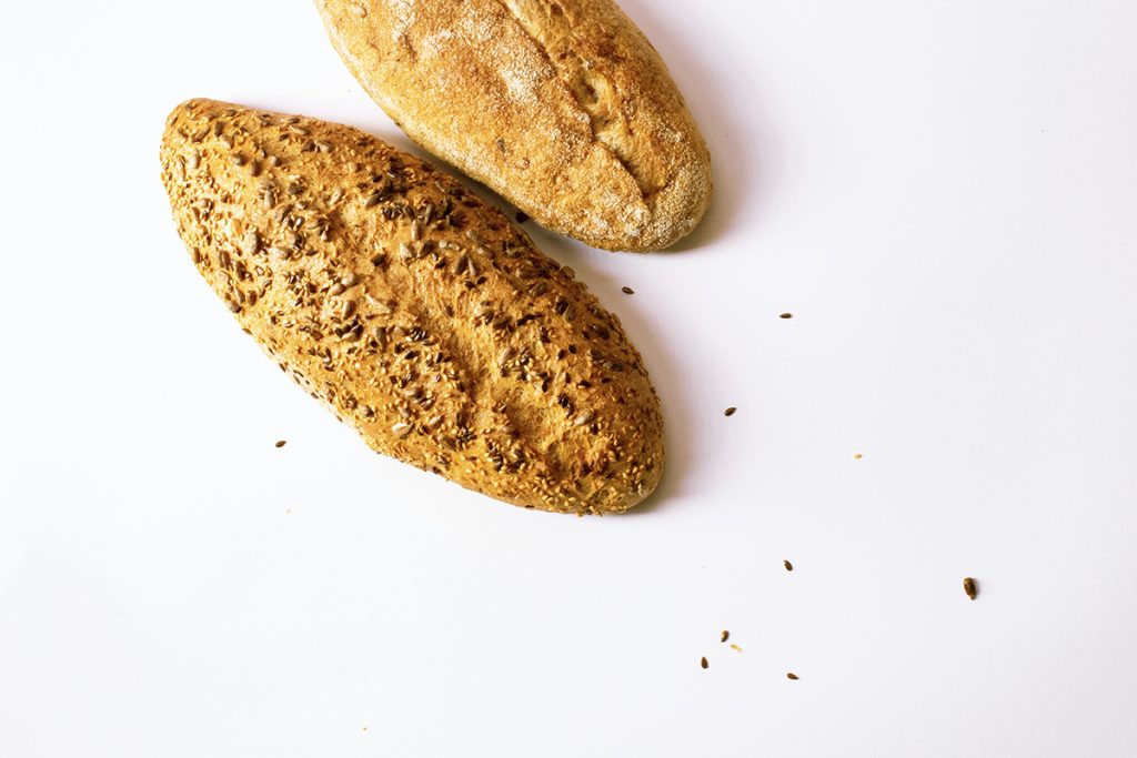Two loaves of bread sit on a white background.