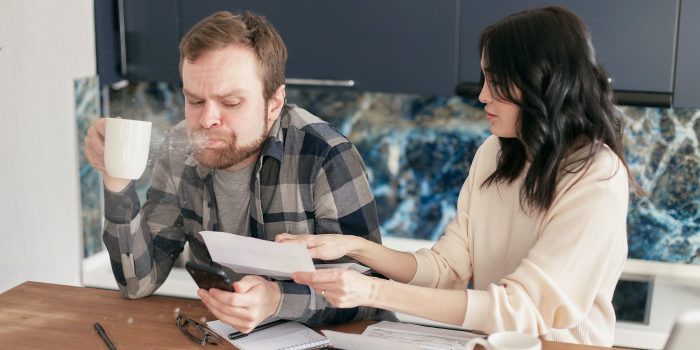 Couple sitting at table doing finances, one is visibly shocked