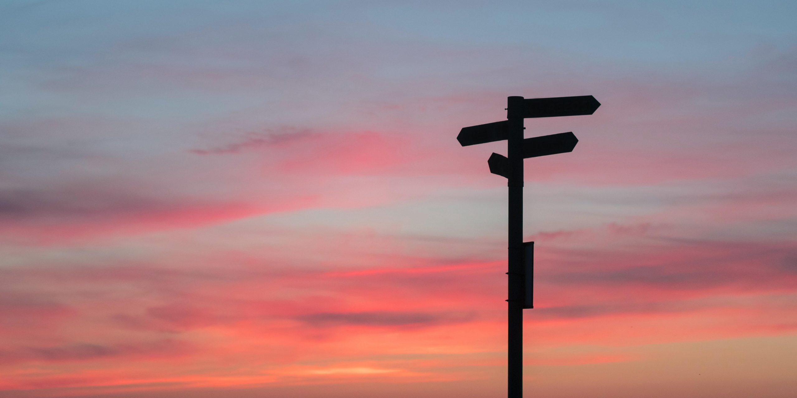 Silhouette of a signpost against the sunset