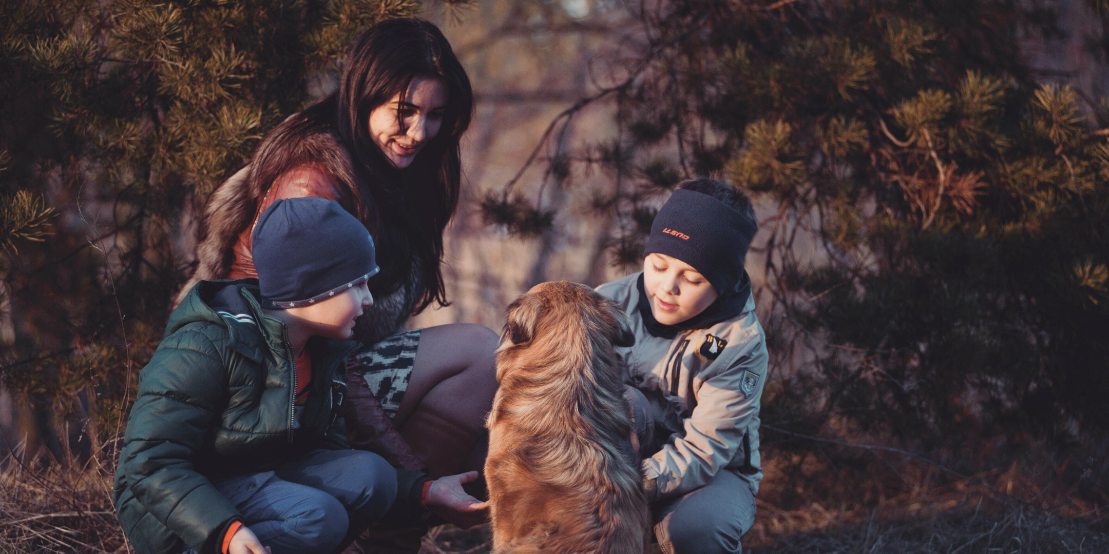 A woman and two boys play with a dog