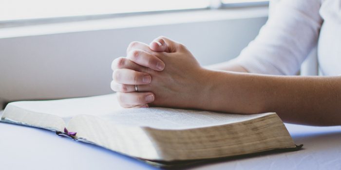hands praying over scriptures