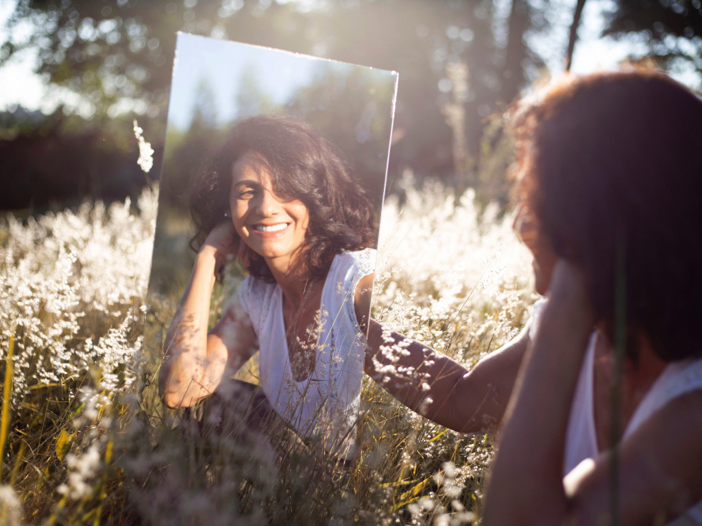 woman looking into mirror outdoors