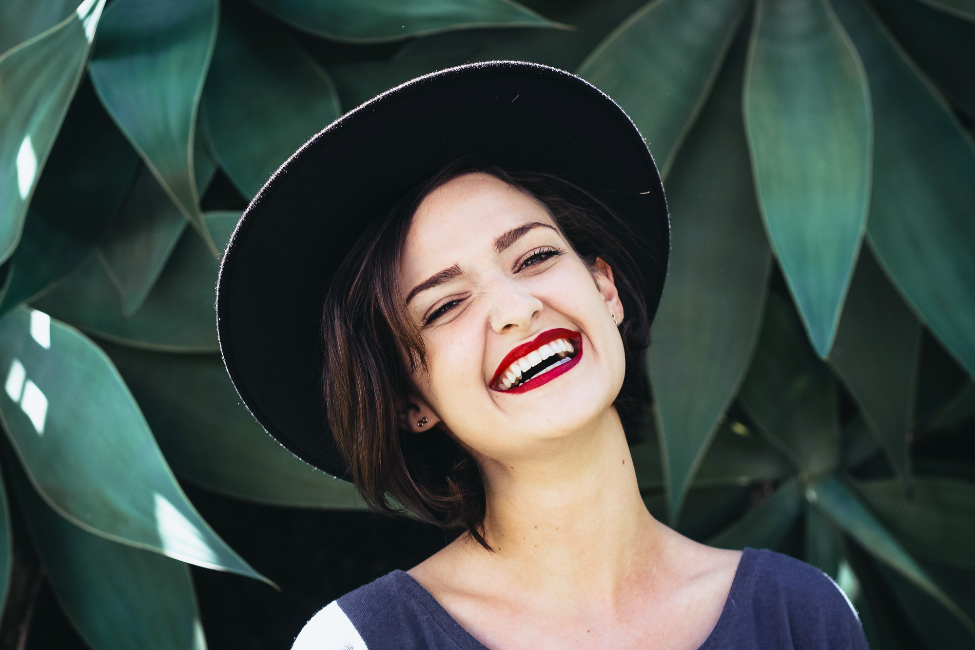 woman wearing a hat and red lipstick smiling