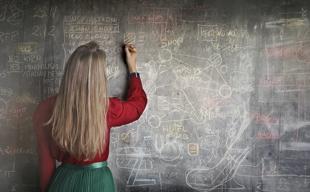 A woman writing on a chalkboard.