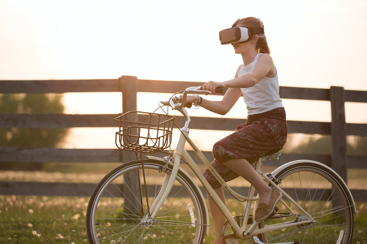 A woman biking down a road while wearing a VR headset.