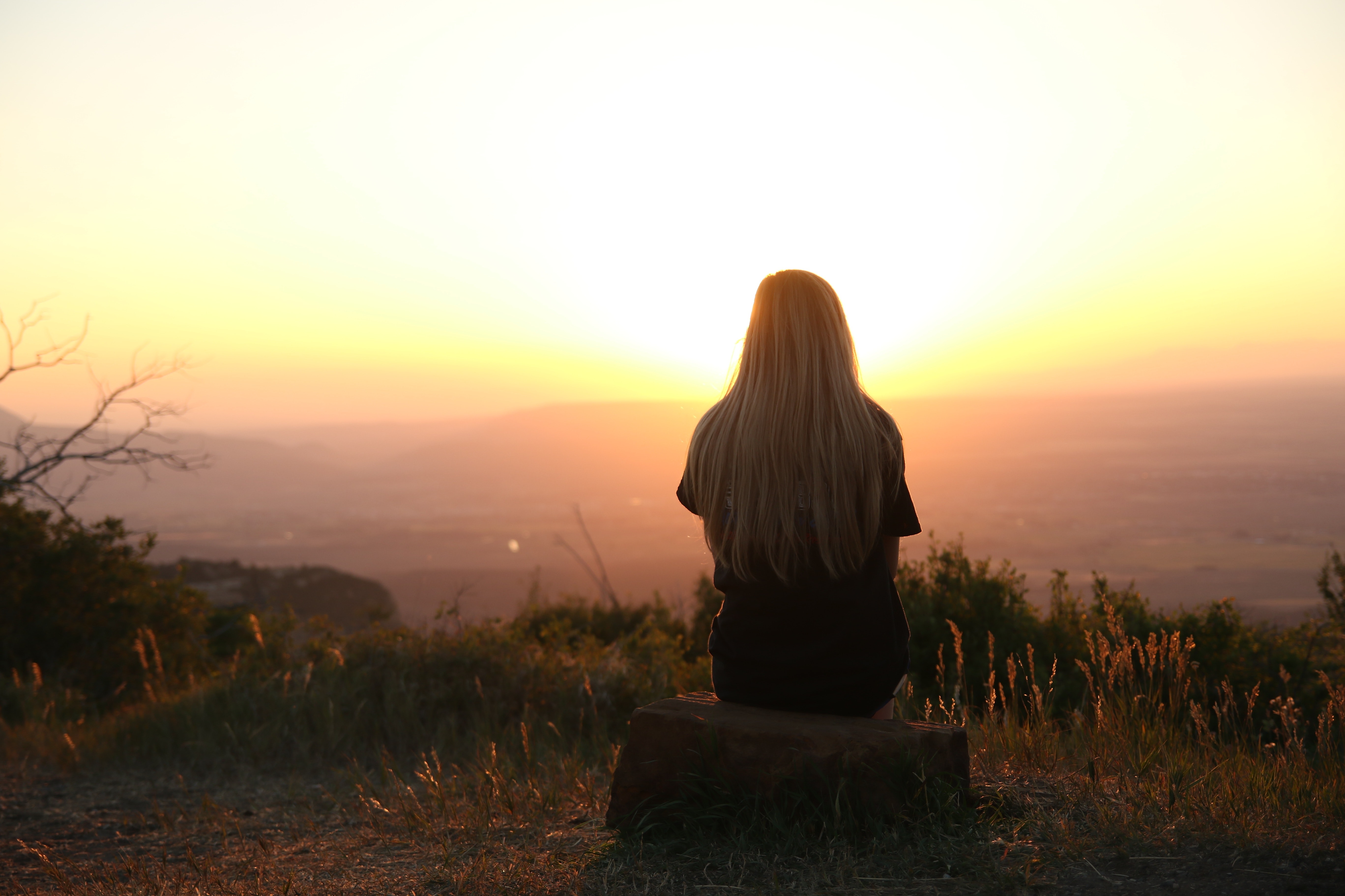 Woman gazing at a sunset on a mountain.