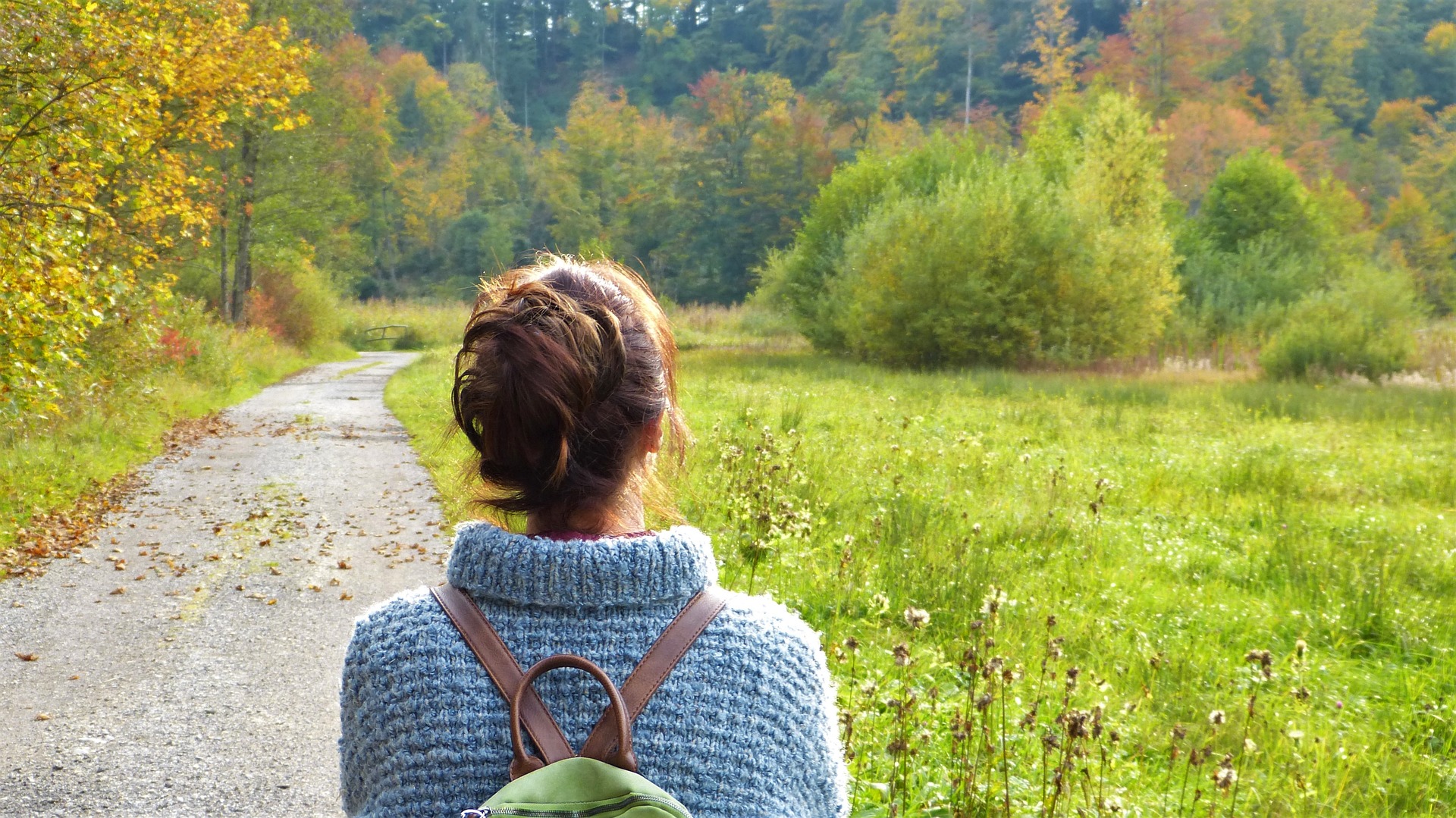 Woman looking at a path in a forest.
