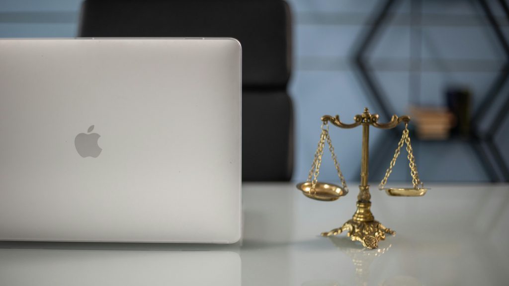 Mini scales of justice next to a laptop