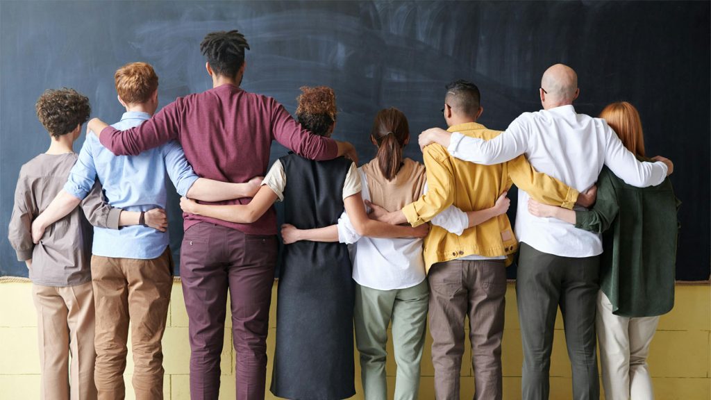 People standing in front of a blackboard with their arms around each other