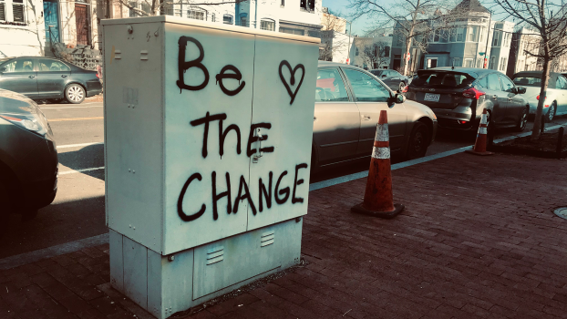 Graffiti on an electrical box that says "Be the Change" with a heart.