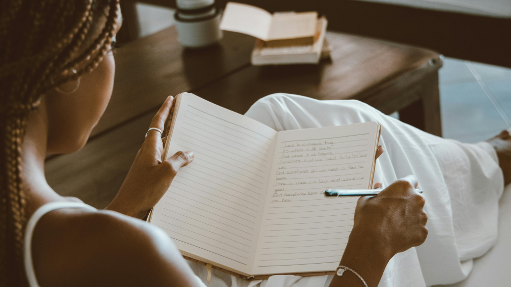 A woman sitting and writing in a notebook.