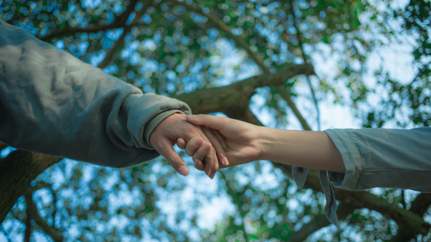 Two people reaching out to hold hands.